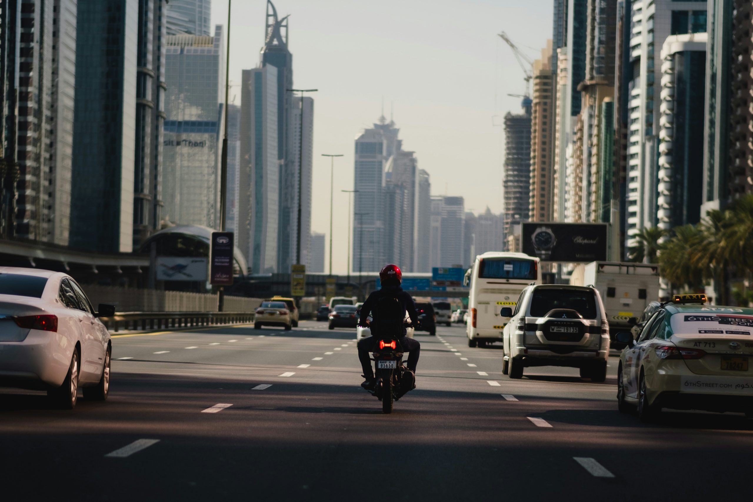 motorcyclist riding along the road surrounded by tall buildings