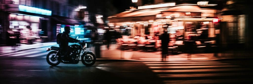motorcyclist riding through an urban area at night.